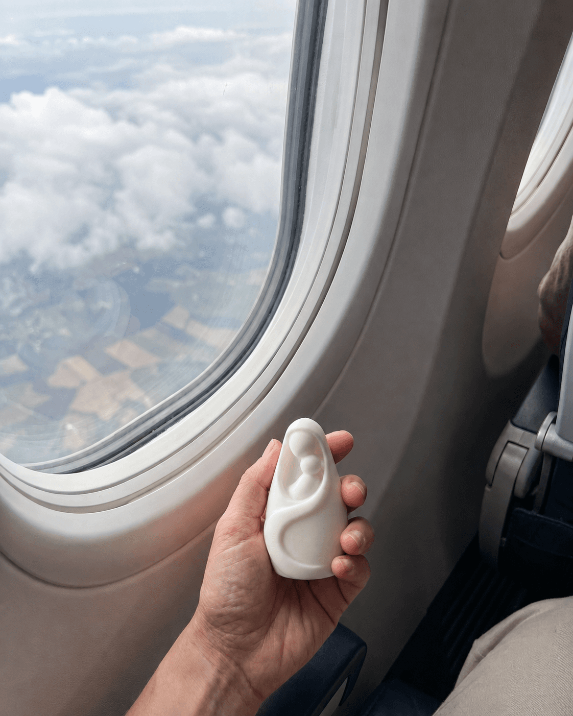 María Cerca sostenida en la mano junto a la ventanilla de un avión, sobre las nubes